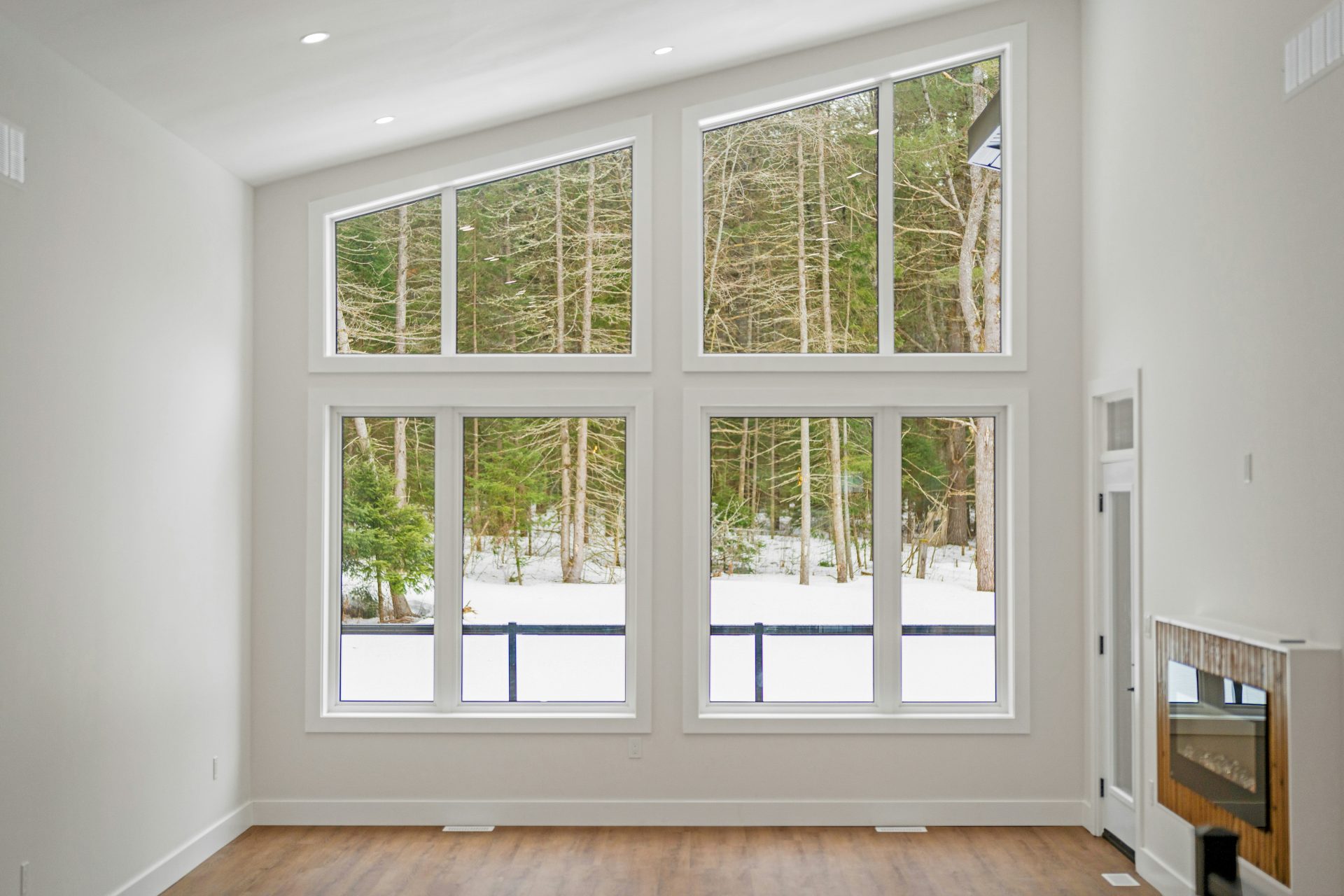Modern living room with large windows overlooking snowy forest